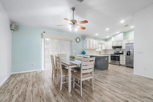 dining space with vaulted ceiling, sink, ceiling fan, and light hardwood / wood-style flooring