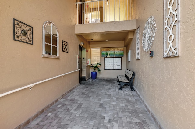 doorway to property featuring a balcony, a patio, and elevator