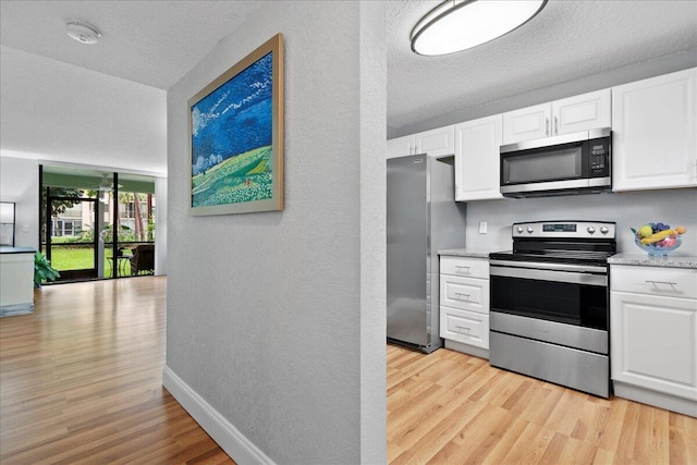 kitchen featuring stainless steel appliances, light wood-type flooring, white cabinetry, and baseboards