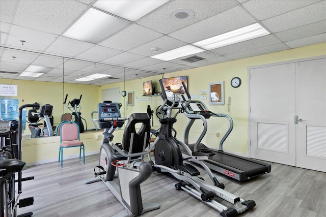 exercise room featuring light wood-type flooring and a paneled ceiling