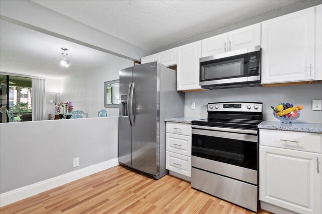 kitchen with light stone counters, a textured ceiling, white cabinetry, appliances with stainless steel finishes, and light wood-type flooring