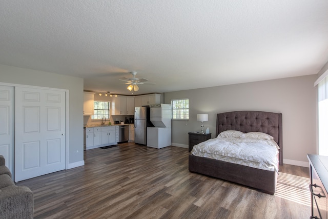 bedroom with dark hardwood / wood-style floors, a textured ceiling, stainless steel fridge, ceiling fan, and a closet