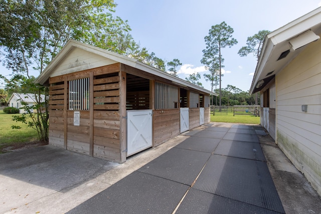 view of stable with a lawn and an outbuilding