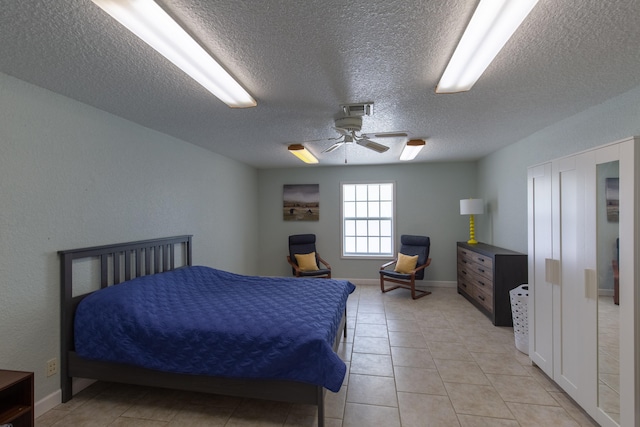 bedroom featuring a textured ceiling, ceiling fan, and light tile patterned floors