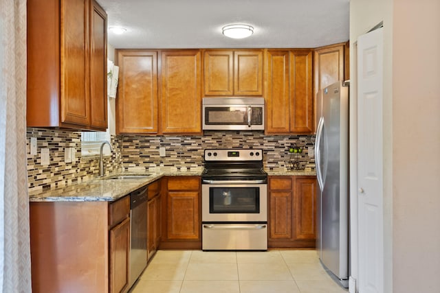 kitchen with sink, stainless steel appliances, backsplash, light tile patterned floors, and light stone countertops