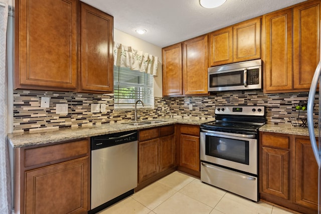 kitchen with light tile patterned floors, sink, a textured ceiling, backsplash, and stainless steel appliances