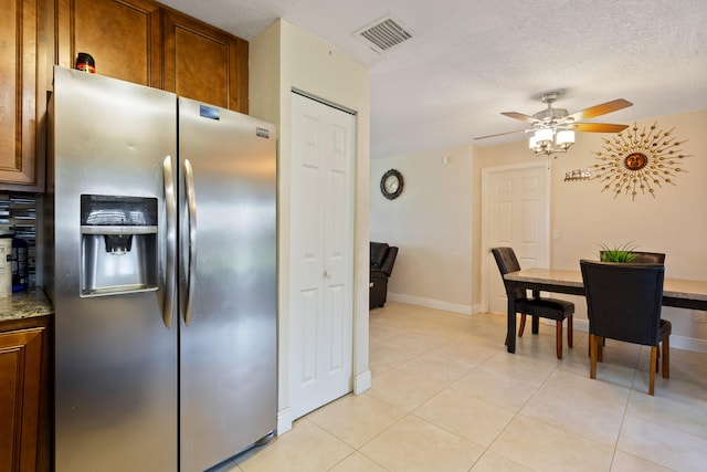 kitchen featuring a textured ceiling, stainless steel fridge, light tile patterned floors, and ceiling fan