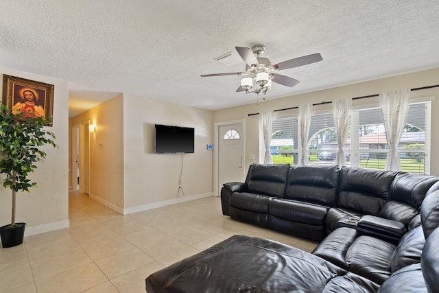 living room with ceiling fan, light tile patterned floors, and a textured ceiling