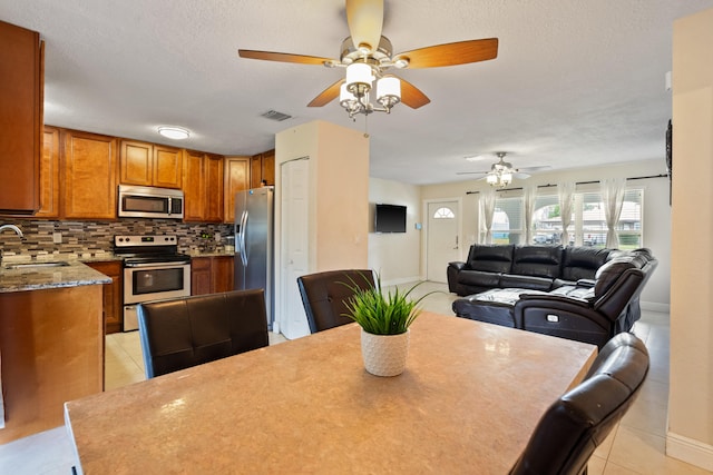 dining space with ceiling fan, light tile patterned flooring, sink, and a textured ceiling