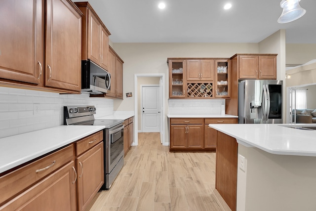 kitchen featuring light hardwood / wood-style floors, appliances with stainless steel finishes, sink, and decorative backsplash