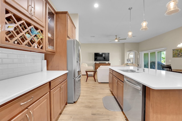 kitchen featuring stainless steel appliances, light hardwood / wood-style flooring, tasteful backsplash, sink, and ceiling fan