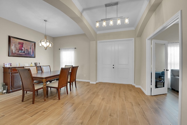 dining area with light wood-type flooring, track lighting, an inviting chandelier, and crown molding