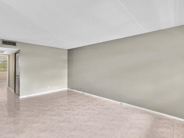 empty room with a textured ceiling and light tile patterned flooring