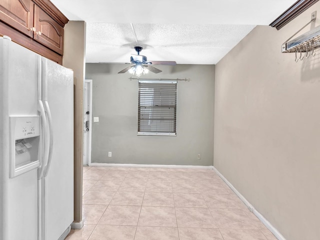 kitchen with light tile patterned floors, ceiling fan, white fridge with ice dispenser, and a textured ceiling