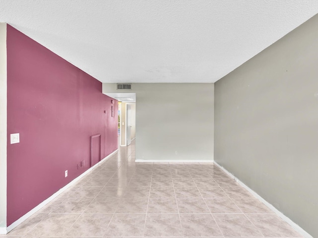 tiled empty room with a textured ceiling