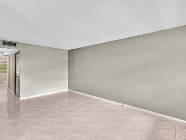 spare room featuring a textured ceiling, visible vents, and baseboards