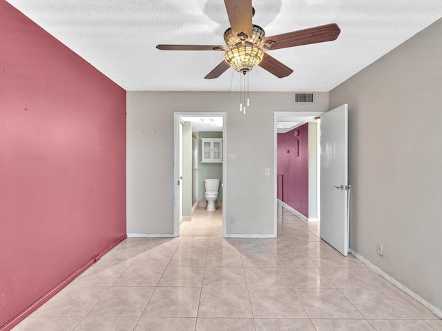 empty room featuring ceiling fan, light tile patterned floors, and a textured ceiling