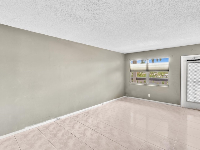 empty room with a textured ceiling and light tile patterned floors