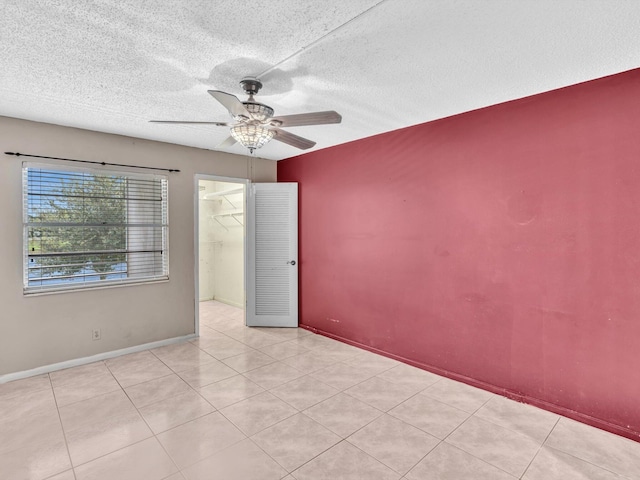 empty room with ceiling fan, a textured ceiling, and light tile patterned flooring