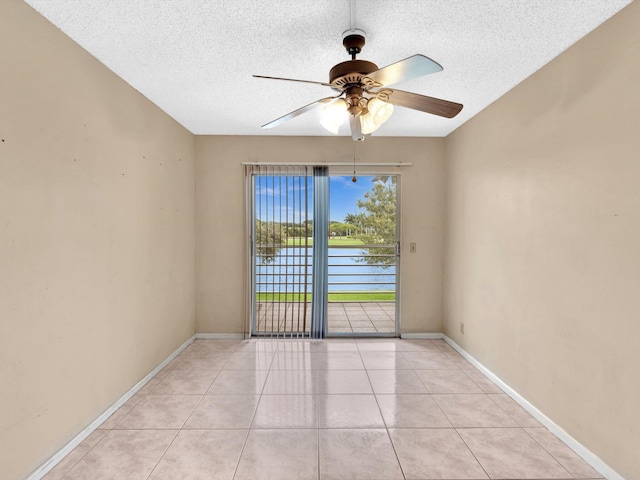 tiled empty room with ceiling fan and a textured ceiling