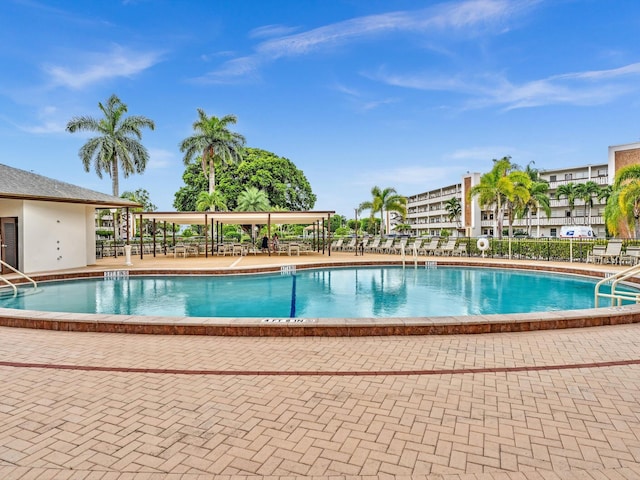 community pool with a patio area and fence