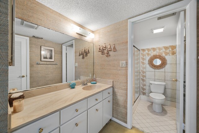 bathroom featuring toilet, vanity, tile walls, a textured ceiling, and a shower with shower door