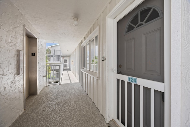 hallway featuring carpet, elevator, and a textured ceiling