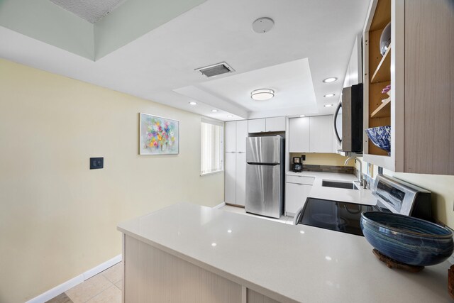 kitchen with light tile patterned floors, appliances with stainless steel finishes, sink, and kitchen peninsula