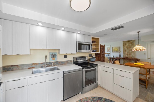 kitchen with light tile patterned floors, sink, decorative light fixtures, kitchen peninsula, and stainless steel appliances