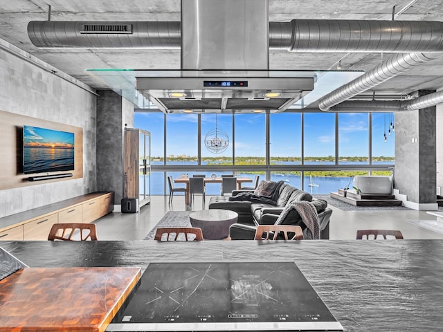 living room featuring finished concrete floors, a water view, visible vents, and floor to ceiling windows