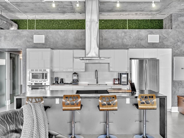 kitchen featuring stainless steel appliances, white cabinets, a sink, and a breakfast bar area