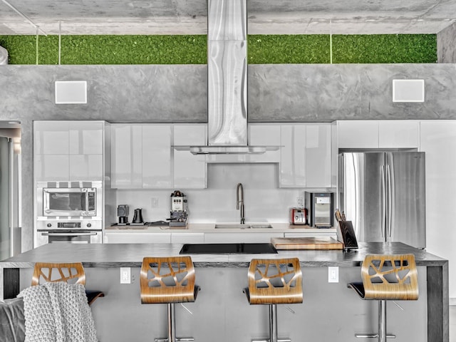 kitchen featuring appliances with stainless steel finishes, white cabinets, a kitchen breakfast bar, and modern cabinets