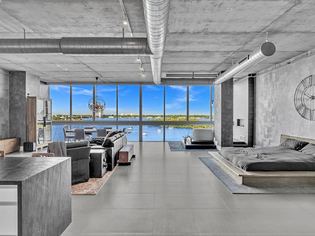 bedroom with multiple windows, a water view, and floor to ceiling windows