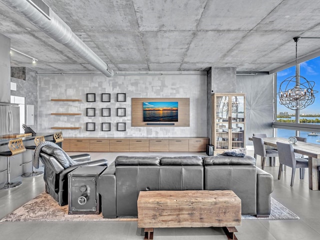 living area featuring finished concrete flooring, expansive windows, and a notable chandelier