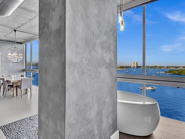 interior space featuring a water view, a freestanding tub, floor to ceiling windows, and a chandelier