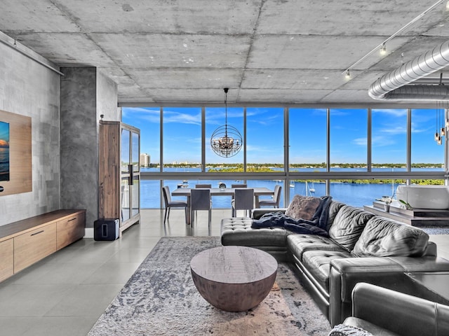 living area featuring a water view, a healthy amount of sunlight, a wall of windows, and a notable chandelier