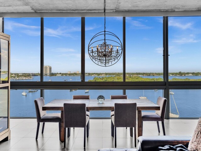 unfurnished dining area featuring expansive windows, a water view, tile patterned flooring, and an inviting chandelier