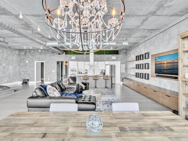 living room featuring concrete flooring and an inviting chandelier