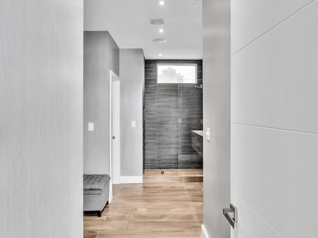 corridor with light wood finished floors, visible vents, and recessed lighting