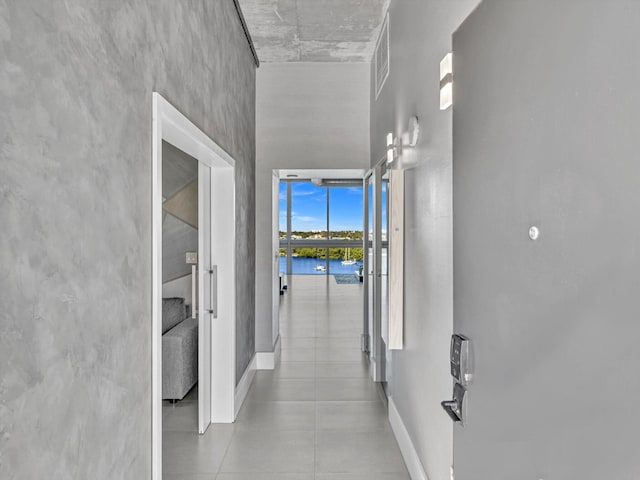 corridor with baseboards, a water view, visible vents, and a towering ceiling