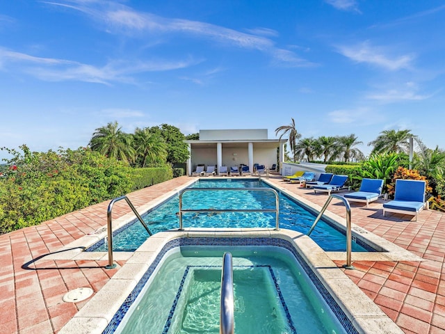 community pool with a patio area and a hot tub