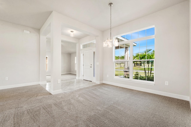 carpeted spare room with a notable chandelier