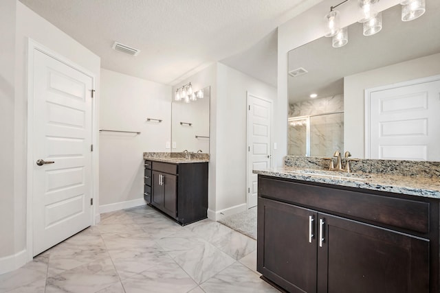 bathroom with vanity, an enclosed shower, and a textured ceiling