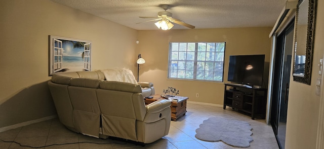 living area with a textured ceiling, light tile patterned flooring, a ceiling fan, and baseboards