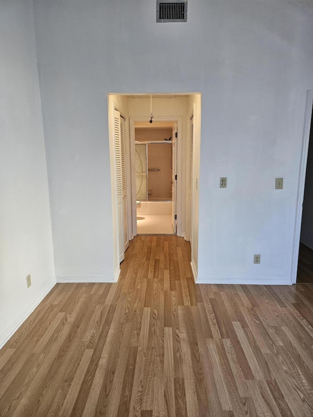 hallway featuring light wood finished floors, visible vents, and baseboards