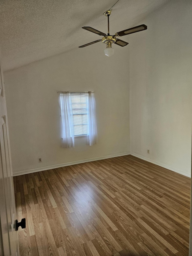 empty room with a textured ceiling, a ceiling fan, vaulted ceiling, and wood finished floors