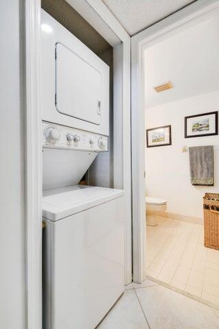 laundry room with stacked washer and dryer, light tile patterned flooring, and laundry area