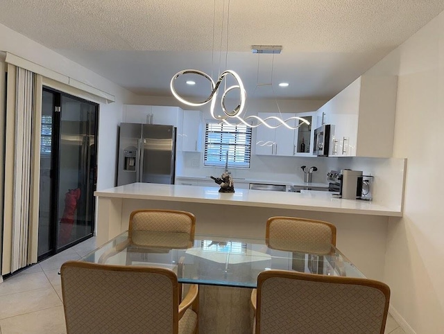 kitchen with a kitchen breakfast bar, white cabinets, appliances with stainless steel finishes, decorative light fixtures, and kitchen peninsula