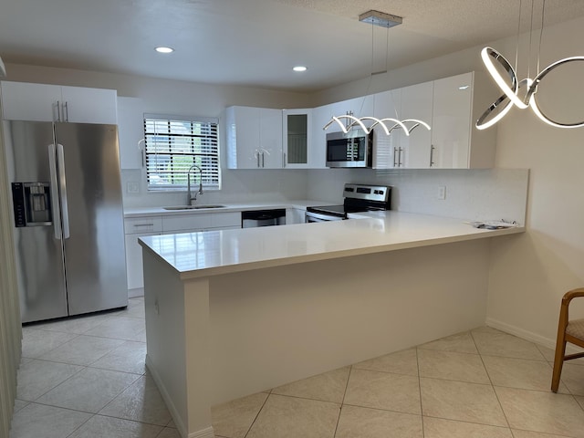 kitchen with light tile patterned floors, light countertops, appliances with stainless steel finishes, a sink, and a peninsula