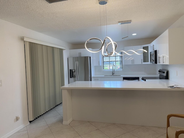 kitchen with appliances with stainless steel finishes, light countertops, a sink, and a peninsula